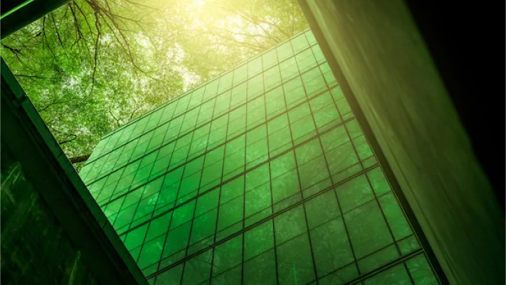 Glass building surrounded by green trees and sunlight